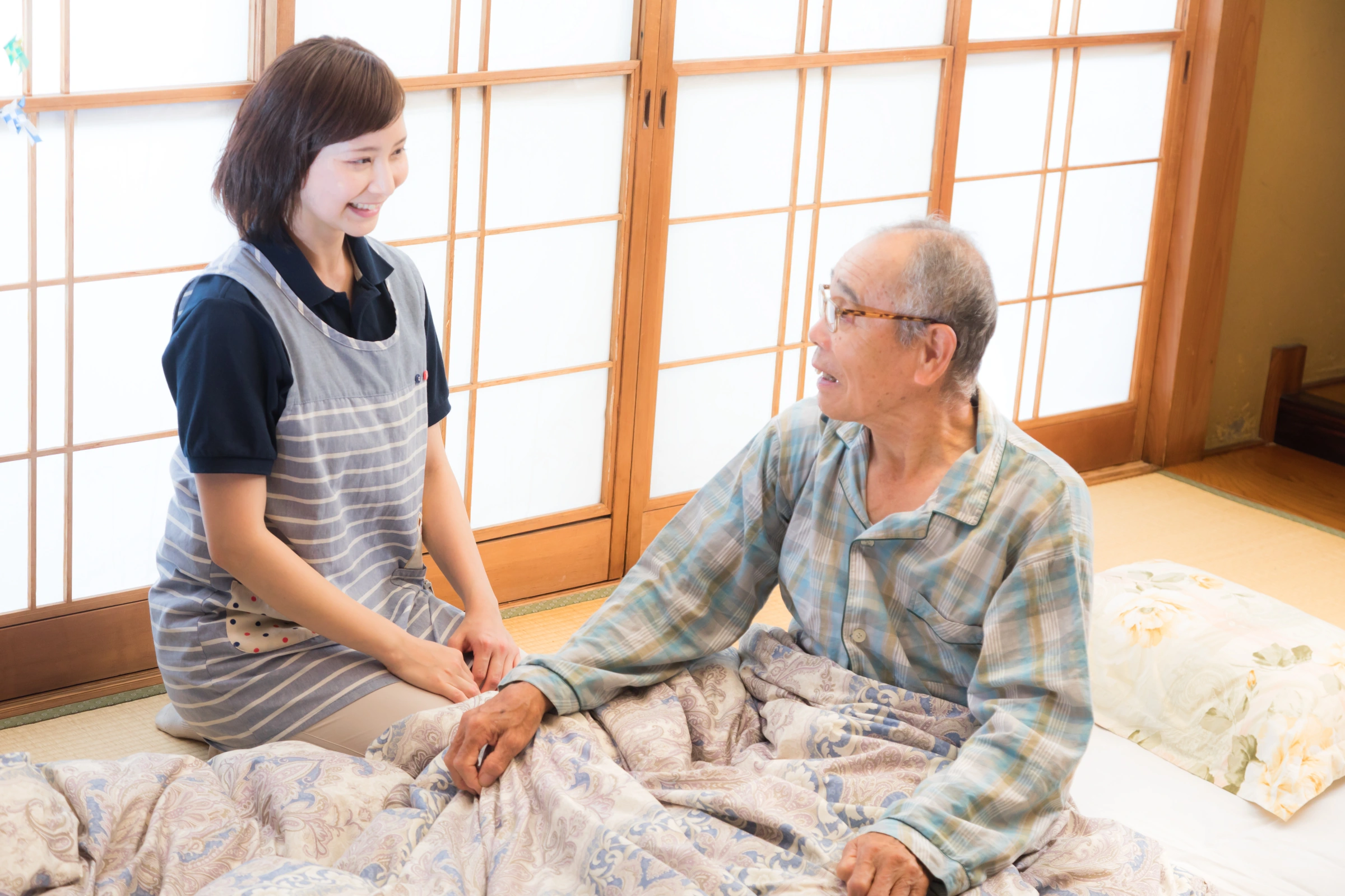 ご自宅で会話をする高齢の男性と介護スタッフのイメージ